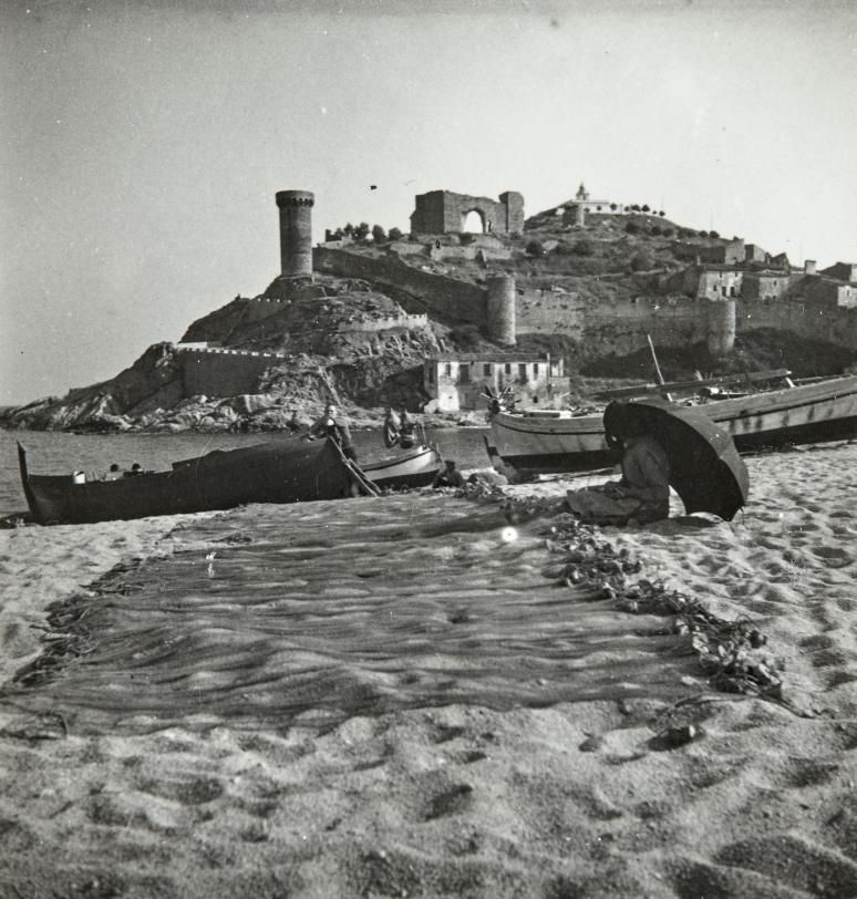 Xarxes estirades a la sorra de la platja de Tossa; al fons, la vila vella, amb un aspecte força diferent de l’actual.