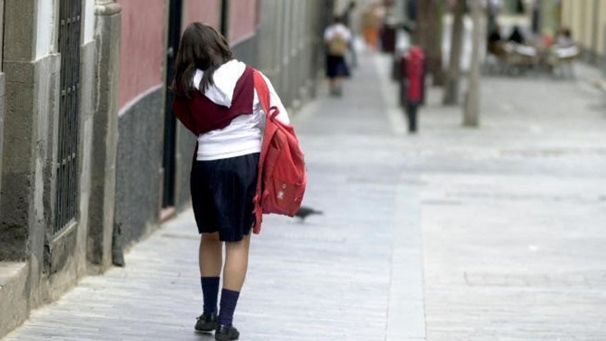 Una escolar con uniforme camina por la calle al final de la jornada lectiva.