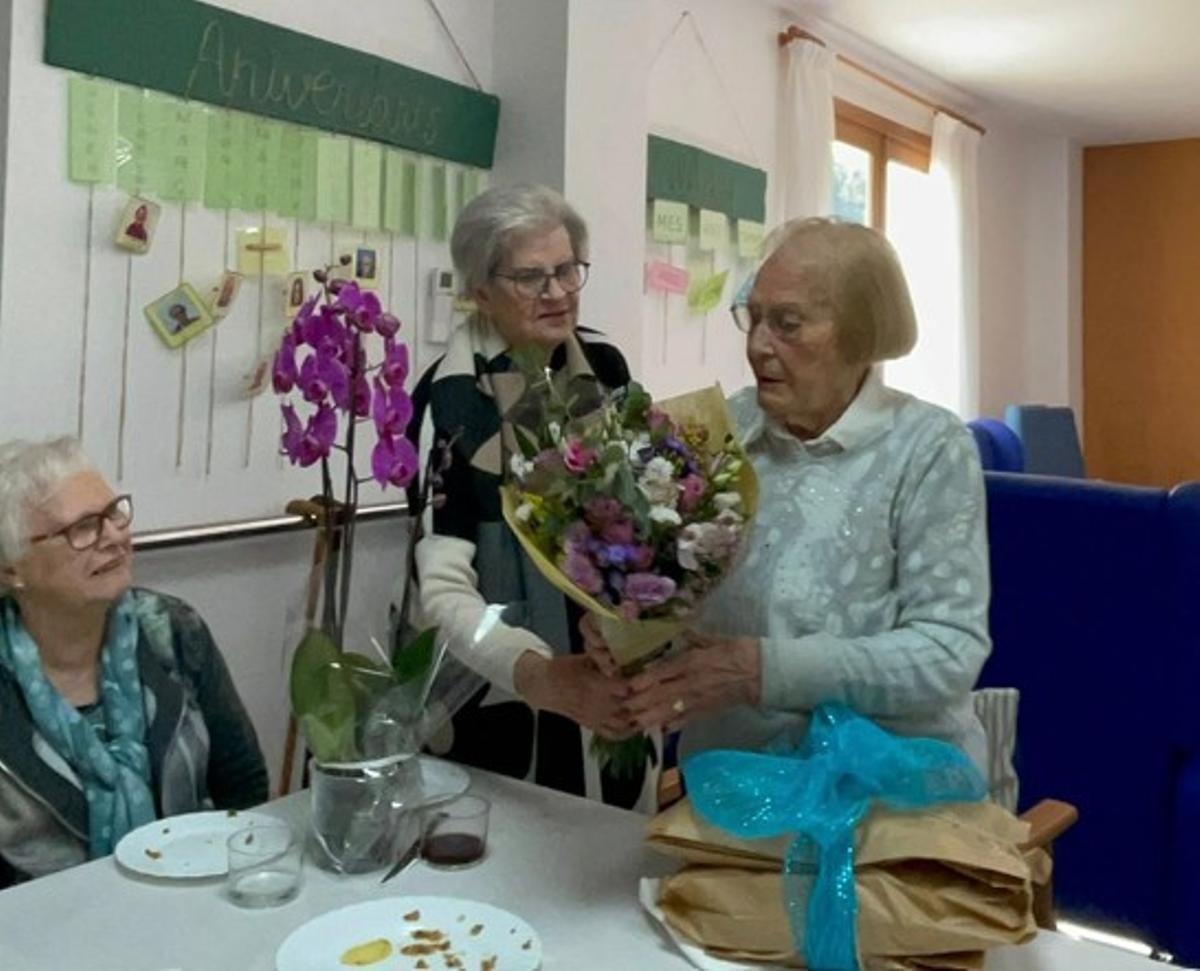 La centenaria recibe un ramo de flores de sus compañeras del centro de día.
