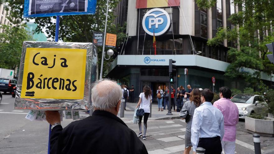 Un hombre se manifiesta delante de la sede del Partido Popular, en la calle Génova de Madrid.