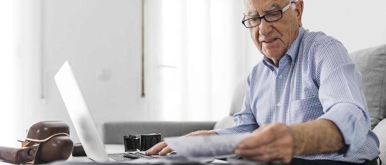 Un hombre mayor con papeles y un ordenador