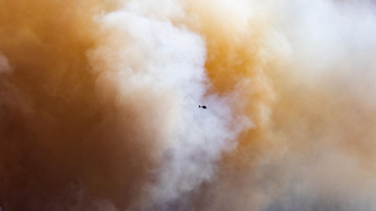 Un helicóptero sobrevuela en el humo del incendio, en La Bisbal d'Empordà, Girona, Catalunya