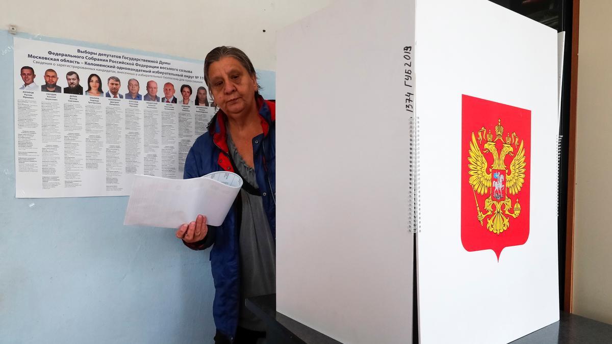 Una mujer sale de una cabina de votación con sus papeletas en un colegio electoral de Novoye Bobrenevo, pueblo de la región de Moscú.