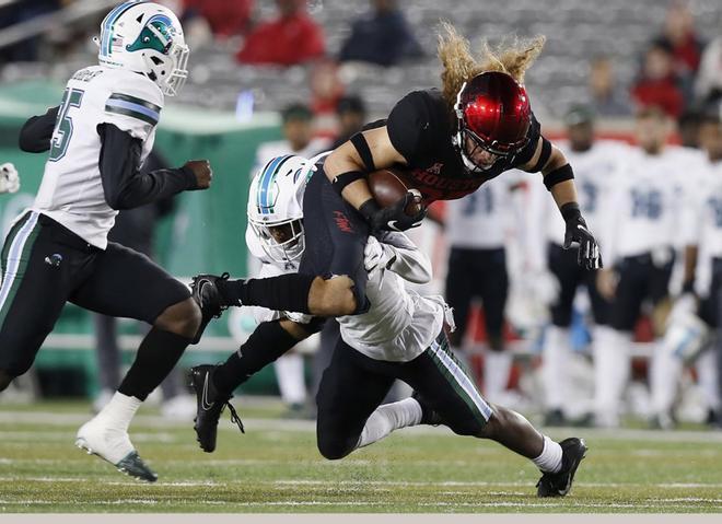 Cougars es abordado por el P.J. Hall # 16 de Tulane Green Wave durante el tercer cuarto del partido, en el estadio TDECU en Houston, Texas.