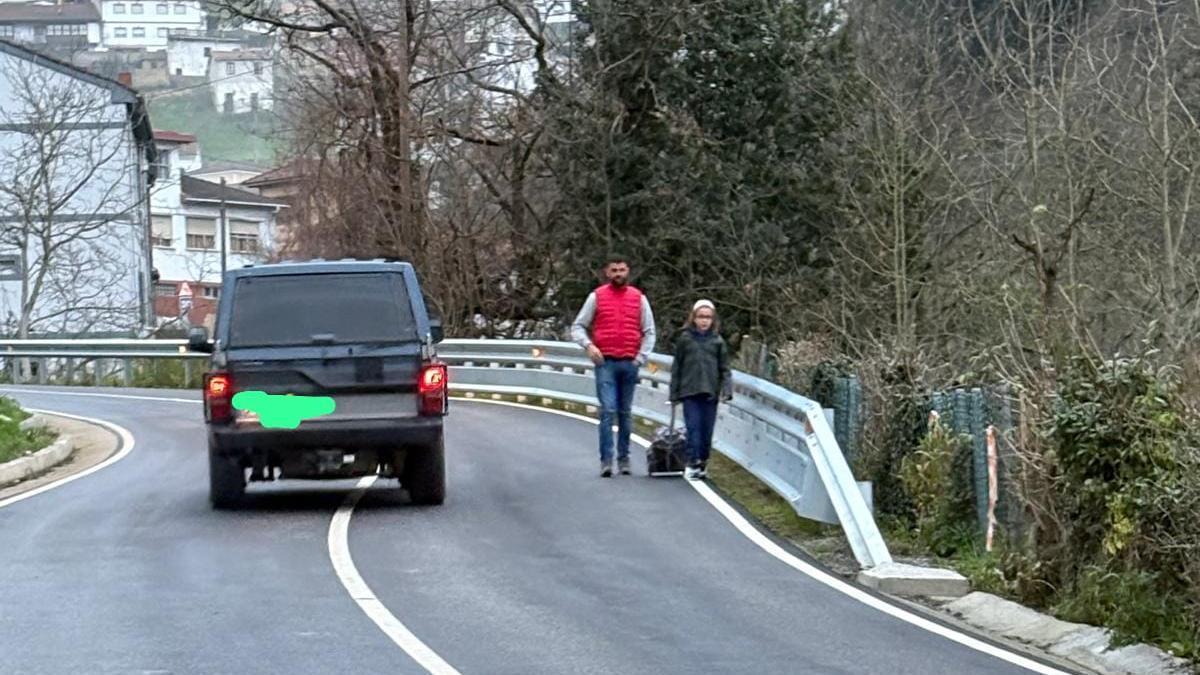 Un padre acompaña a su hija al colegio transitando entre los coches.