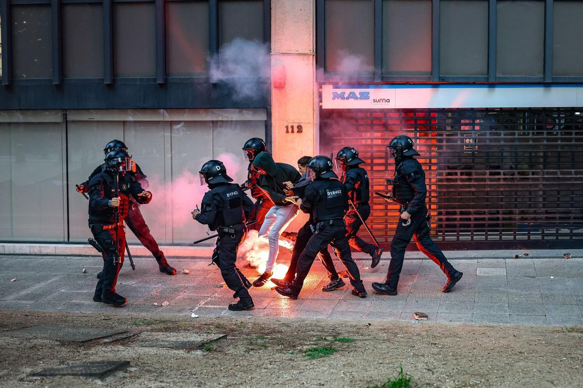 Mossos dEsquadra agafen un activista davant dunes flames durant una manifestació a favor de Palestina a Barcelona