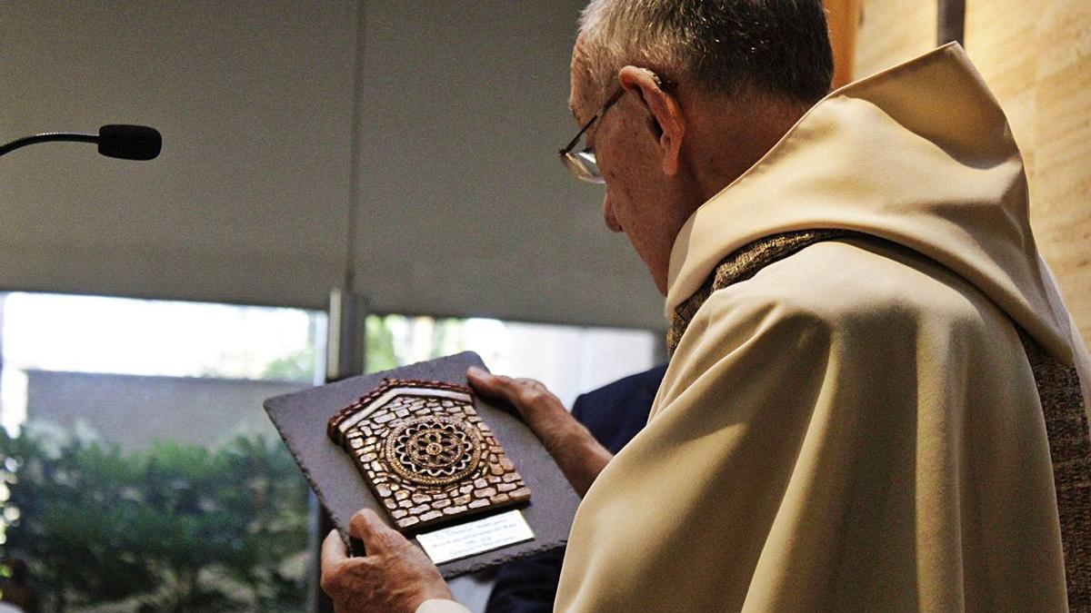 El sacerdote Silverio Rodríguez Zapico, ayer, mirando la placa que le ha regalado el barrio de Laviada por sus  50 años al frente de la parroquia. | Daniel Mon