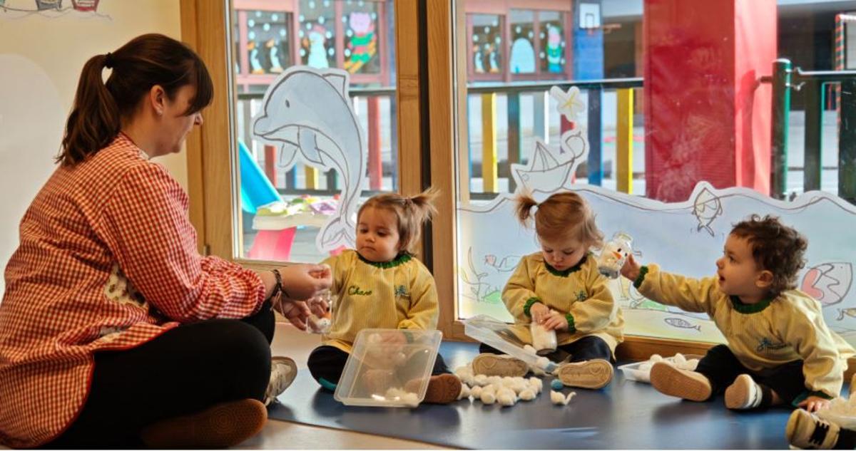 Por la izquierda, una de las profesoras del centro con tres pequeños realizando una actividad