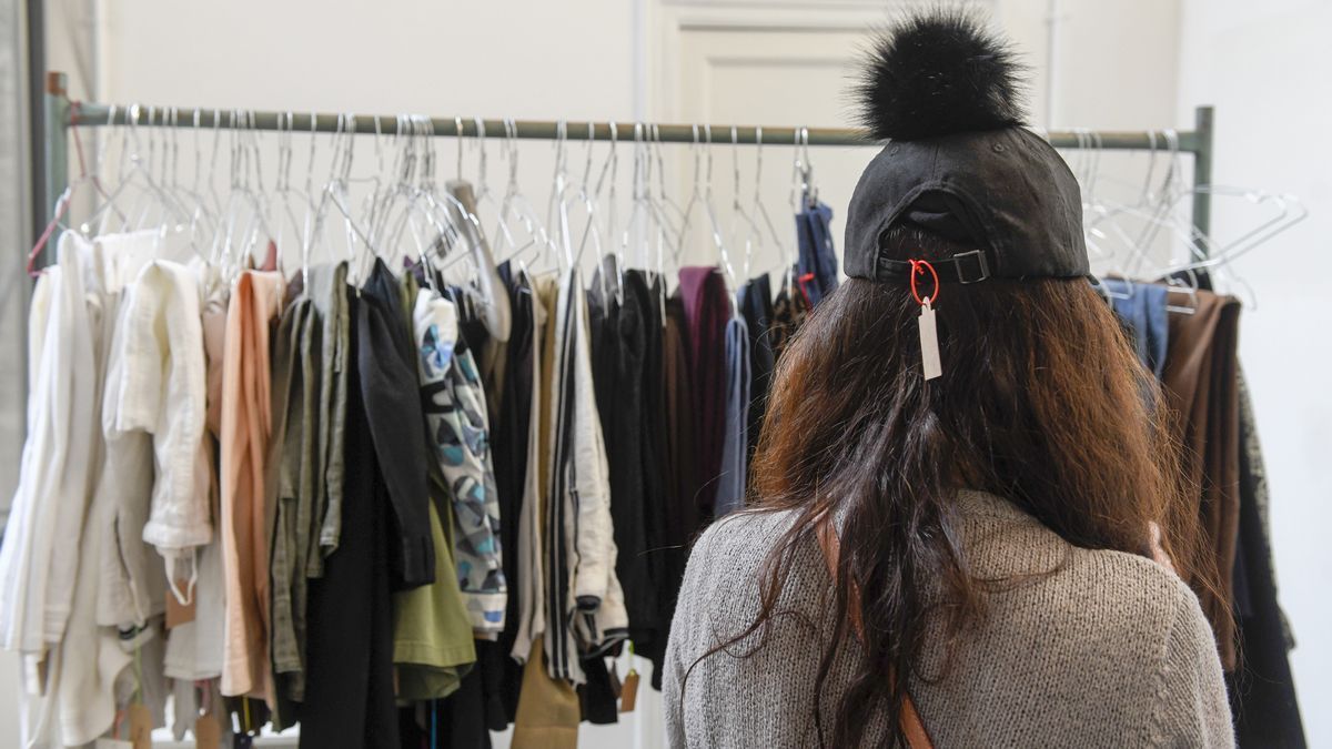 Una mujer acude al mercadillo 'baúl weekend' de ropa de marca de segunda mano donada.