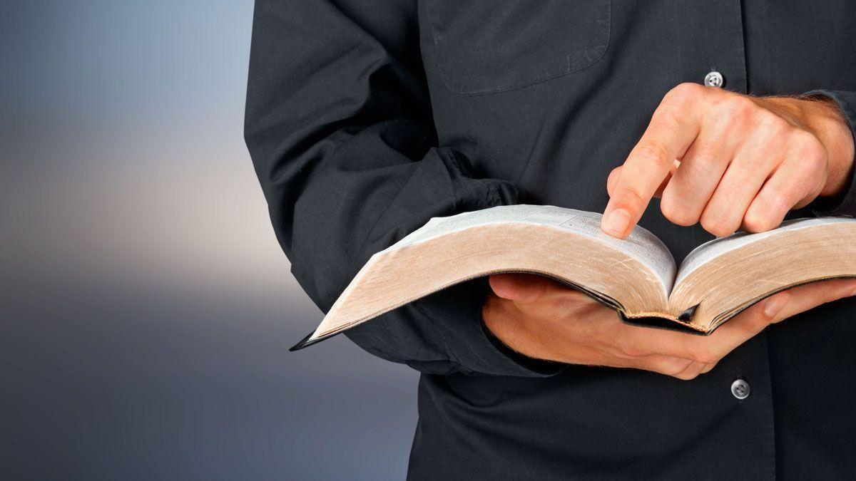 Un sacerdote con un libro de texto en la mano.