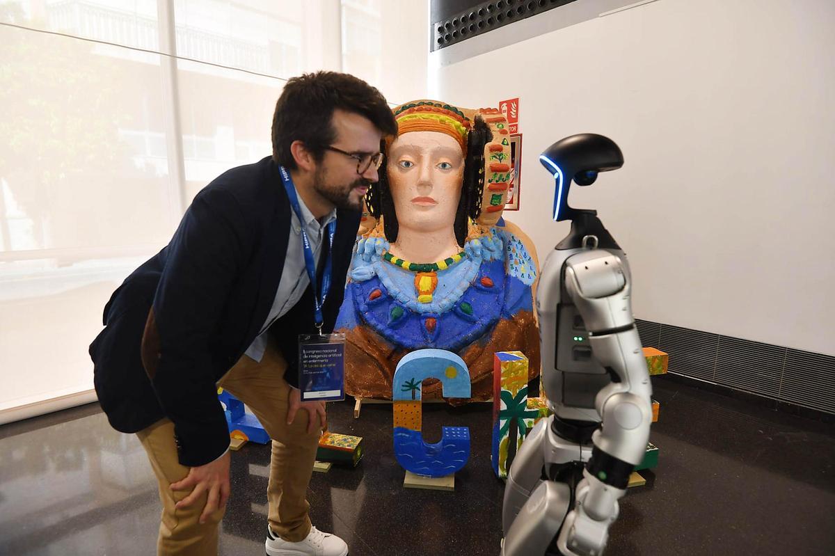 El influencer Marius Lekker mira cara a pantalla al robot Humanoid G1 de Unitree Robotics en presencia de un busto de la Dama de Elche durante el congreso de IA y Enfermería