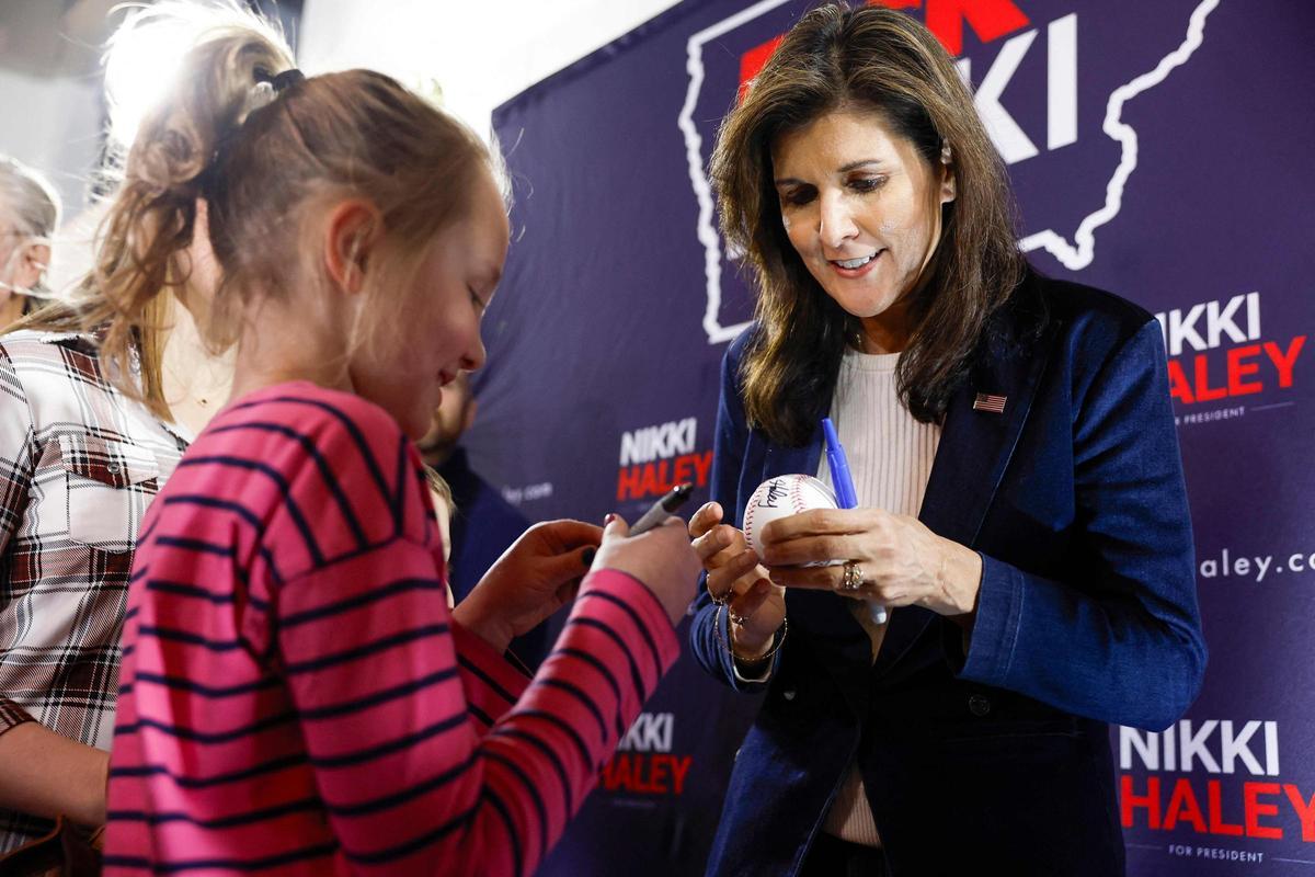 Nikki Haley firma una pelota de béisbol a una niña, durante el acto con simpatizantes en Cedar Rapids, Iowa.