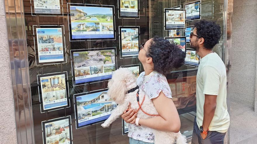 Dos jóvenes miran la oferta de pisos en una inmobiliaria. |   // ALBA VILLAR
