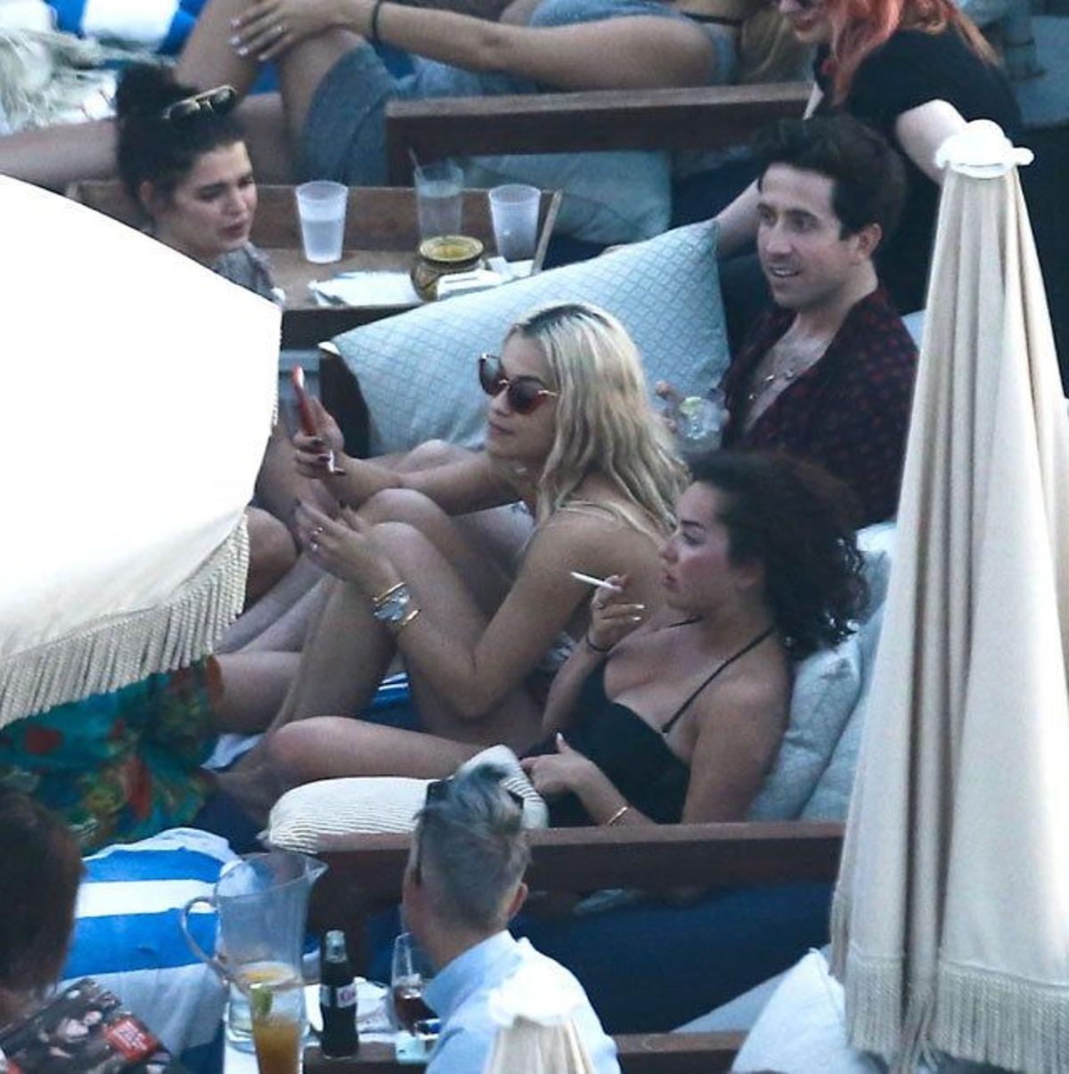 Rita Ora se incorpora de la tumbona para hablar con sus amigos