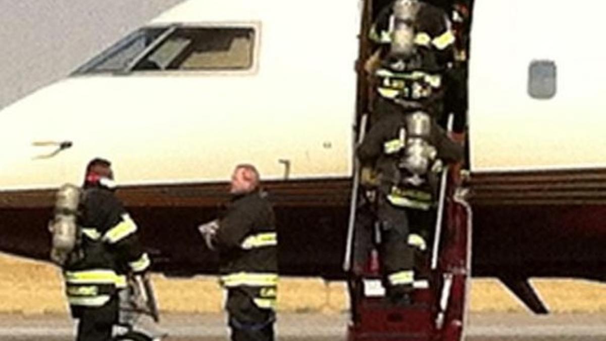 Los bomberos suben al avión que trasladaba a Ann Romney.