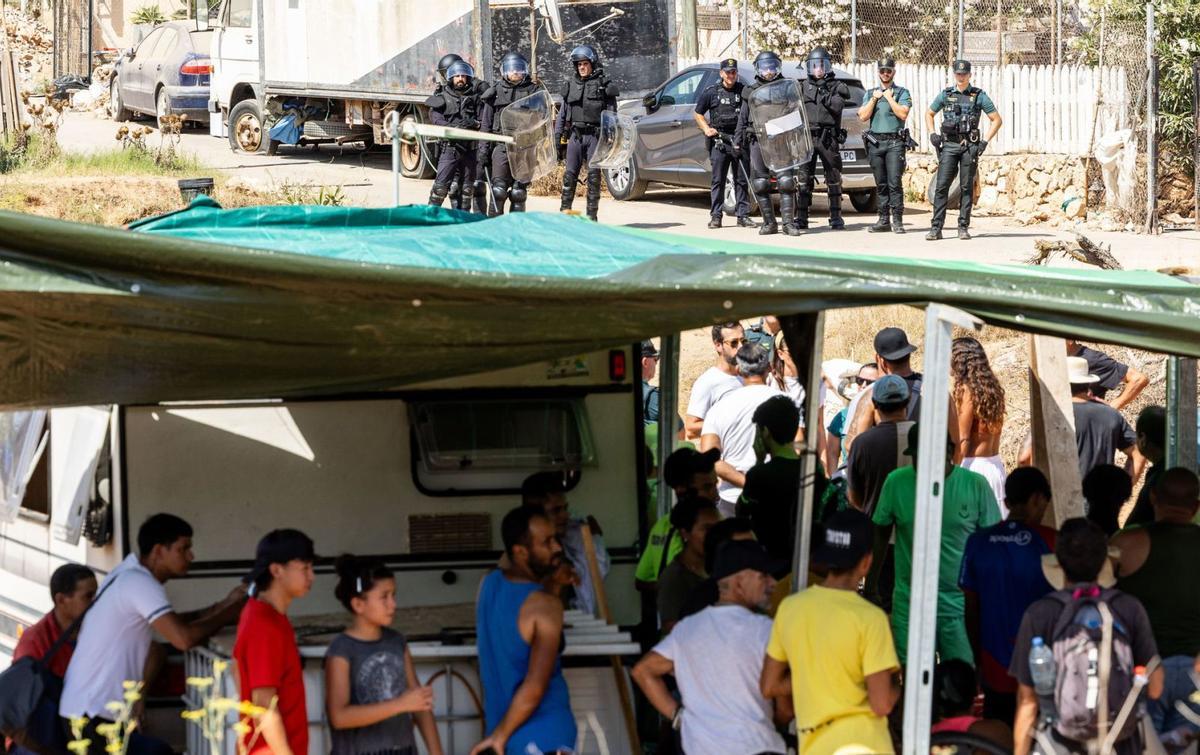 Los desalojados de Can Rova, atrincherados bajo un toldo y, al fondo, los antidisturbios.