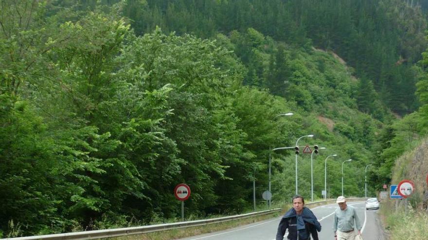 Dos personas pasean por la carretera a la salida de Corias.