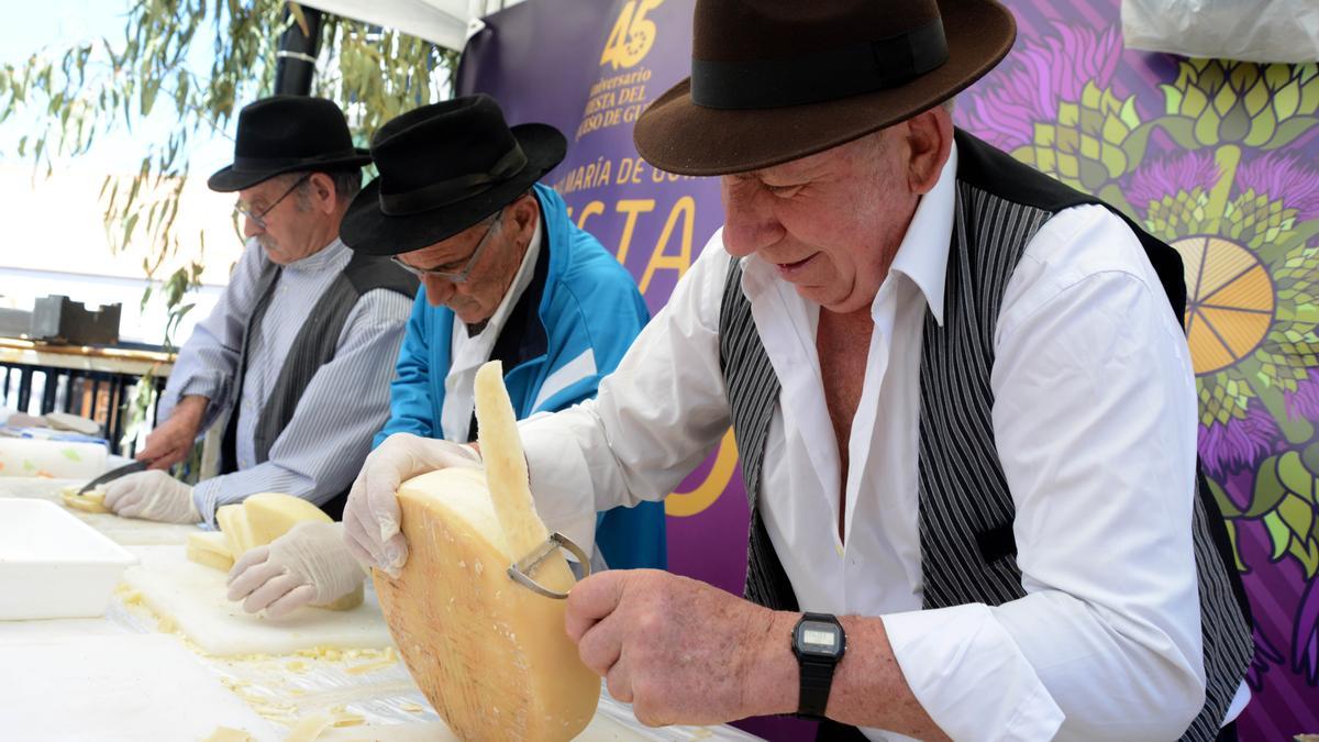 Tres artesanos cortan queso en la fiesta de Montaña Alta.