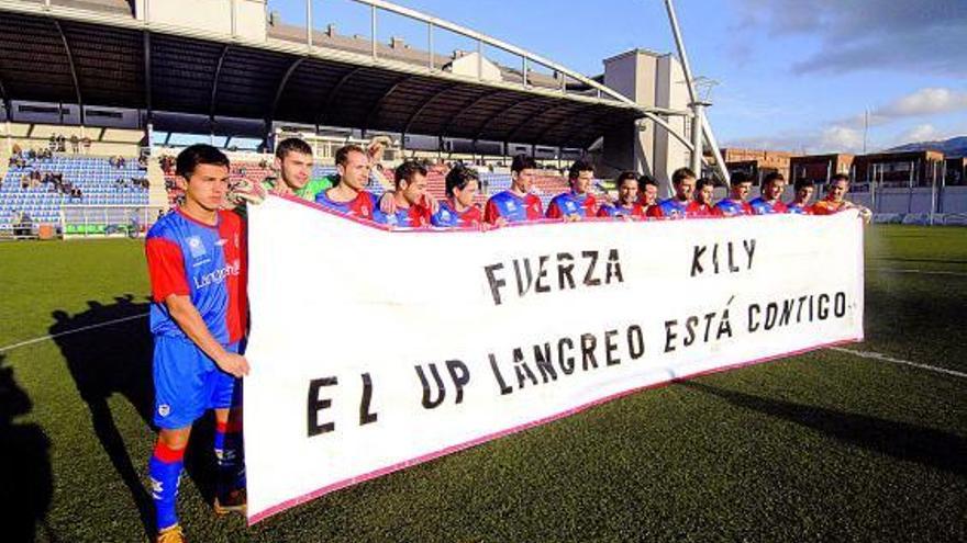 Los jugadores del Langreo muestran una pancarta en favor de Kily antes de comenzar el partido ante el Candás.