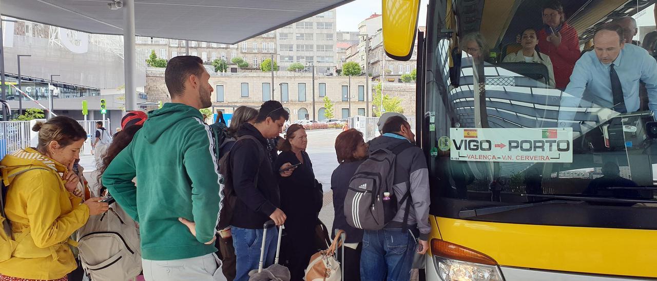Viajeros ante un autobús que cubre la ruta entre Vigo y Oporto en la estación intermodal.