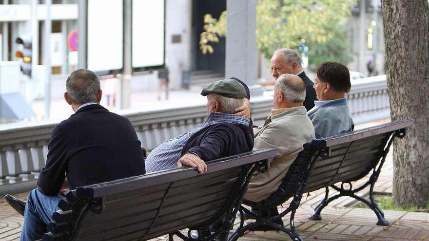 Varios jubilados, sentado en los bancos de un parque.