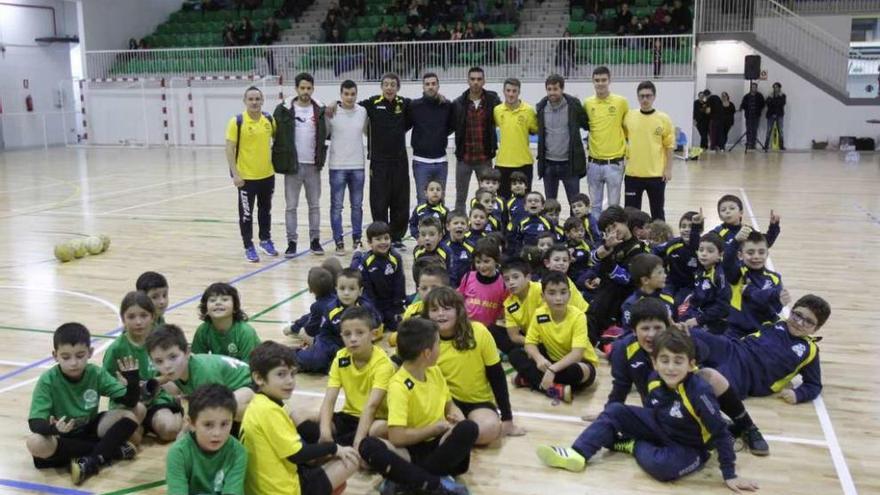 Los niños del club Grupo Casa Paco 81, y al fondo los jugadores Pablo Couñago, Iago Bouzón, Mateo, Yeray y Caloi junto a los entrenadores del equipo, ayer, en la fiesta de Nadal en el nuevo pabellón. // José Lores