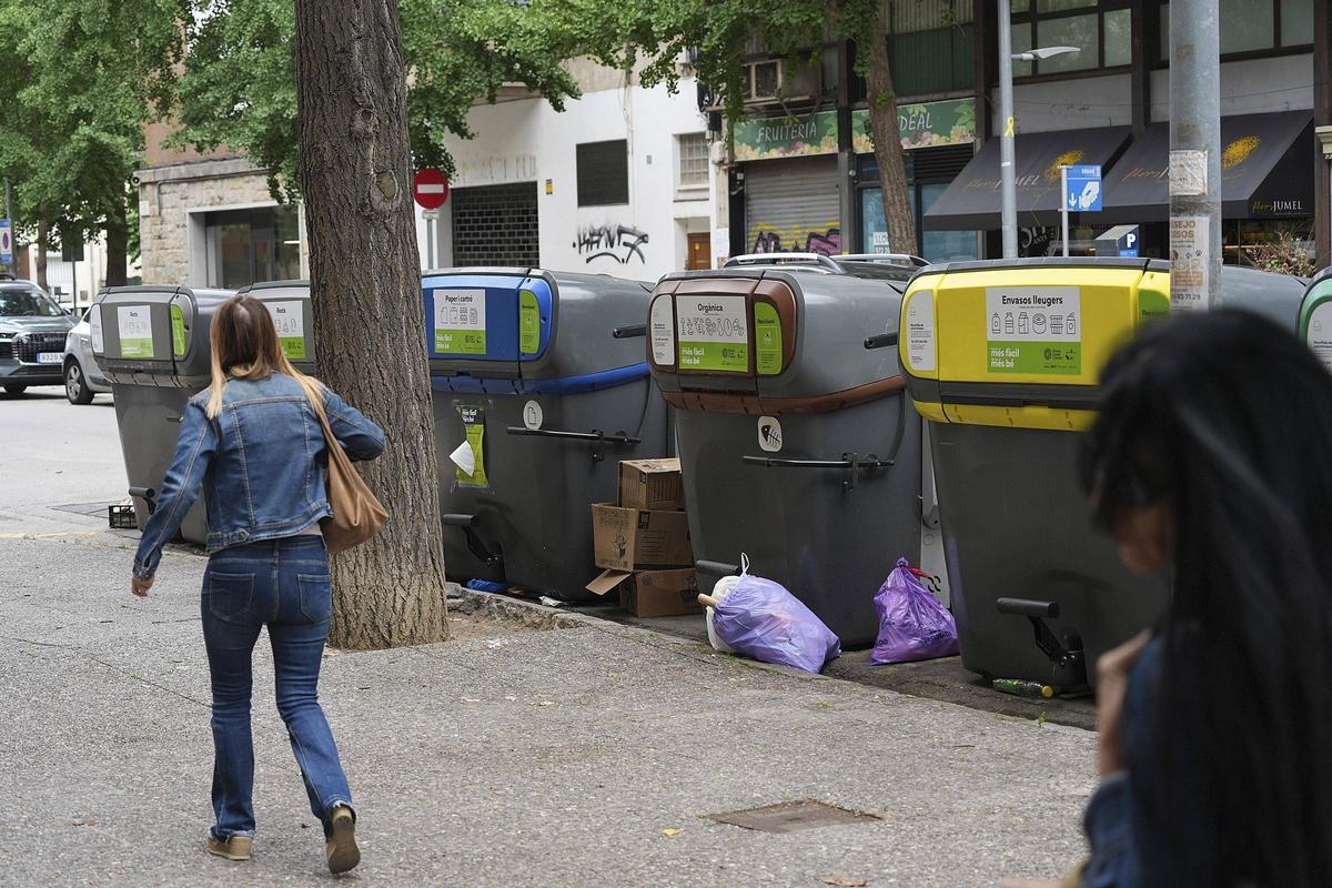Contenidors al carrer de la Creu amb algunes deixalles fora, aquest dimecres.