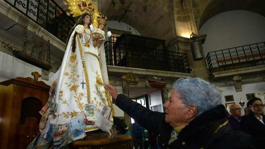 Una mujer coloca un billete en el manto de la santa. // G. Santos