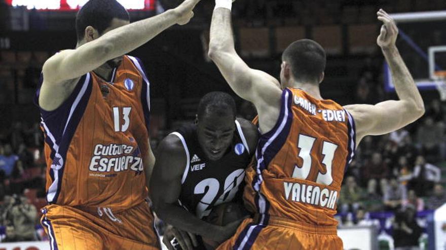 El base estadounidense del VEF Riga, Maurice Bailey (c), trata de superar la defensa de los pivots del Valencia Basket, el brasileño Victor Faverani (i) y el estadounidense Nik Caner-Medley, durante el segundo partido de la segunda fase de la Eurocopa de baloncesto disputado esta noche en el pabellón de la Fuente de San Luis de Valencia.