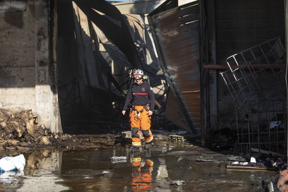 Los bomberos siguen trabajando en la nave del Port de Sagunt un día después del incendio