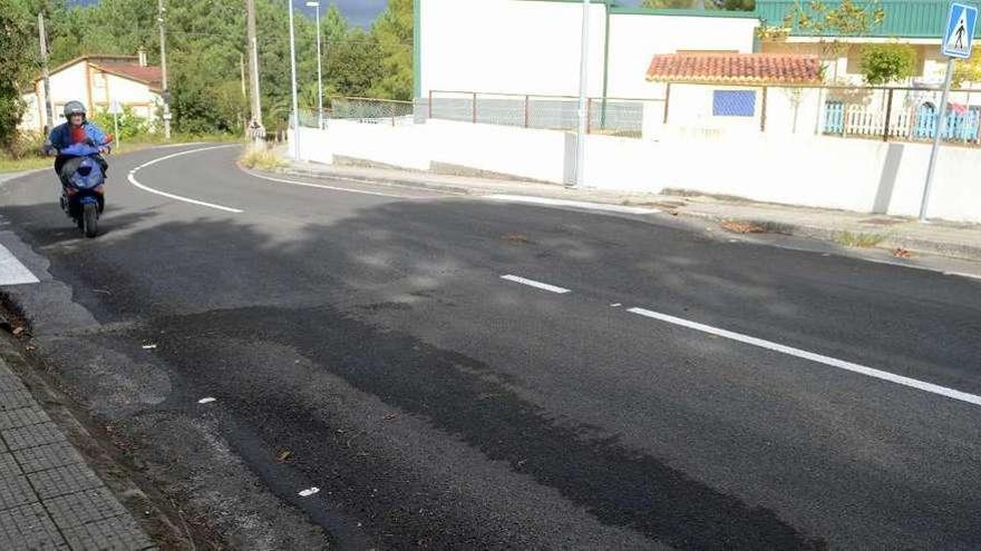 La carretera que pasa ante el colegio, el instituto, la zona deportiva y el centro de salud de Baño (Valga). // Noé Parga