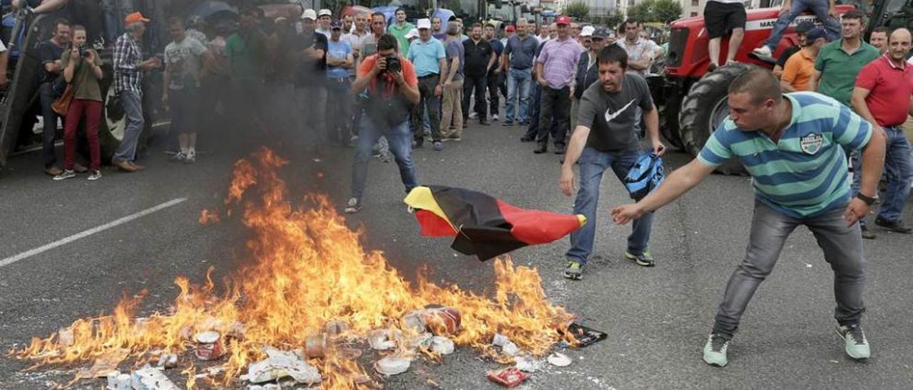 Manifestantes el martes en Santiago de Compostela quemando una bandera alemana.