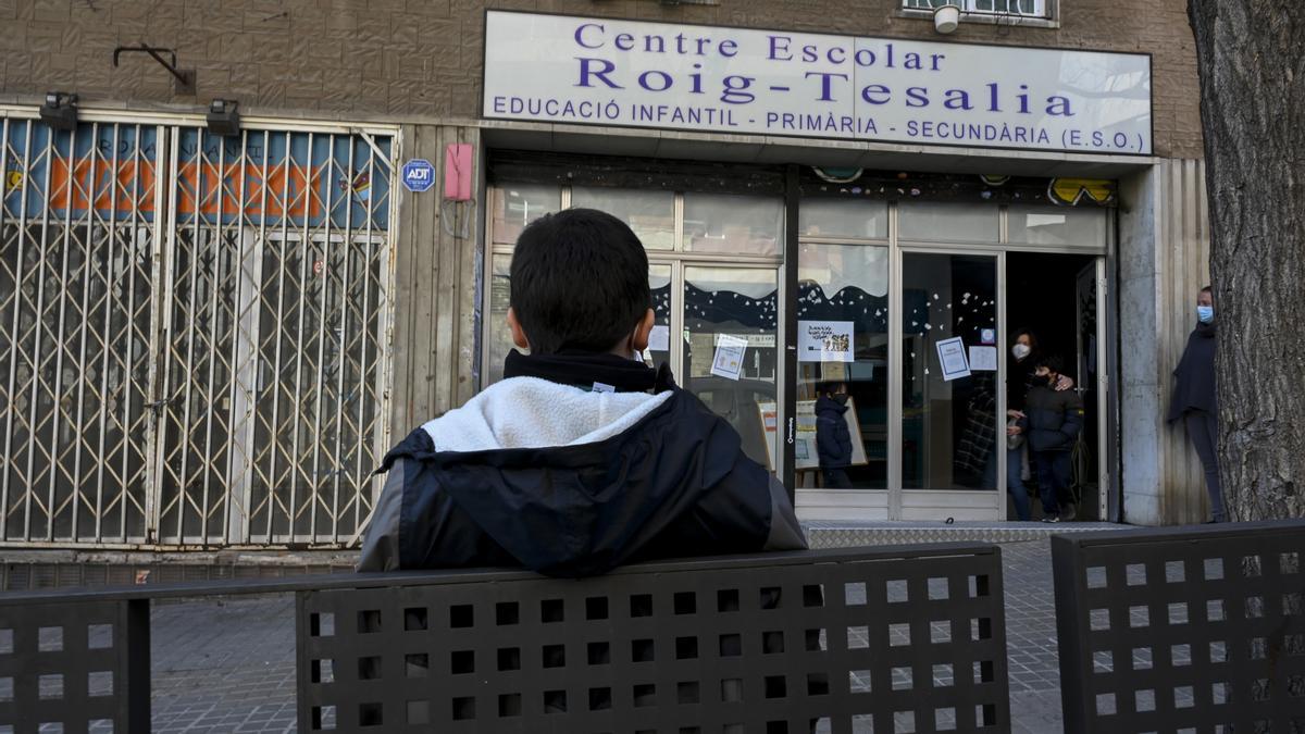 Eric, de espaldas, frente al colegio Roig Tesalia de Barcelona, que cierra este curso.