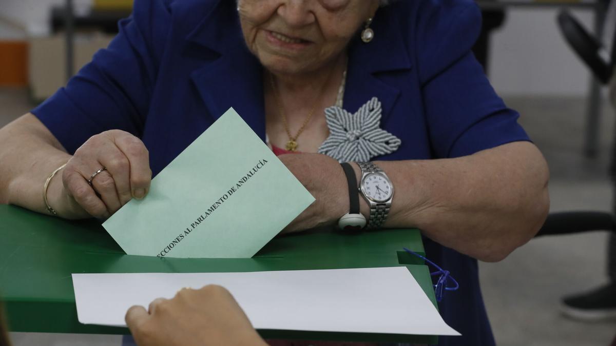 Una mujer introduce su papeleta de voto en el colegio electoral de la SAFA de Sevilla