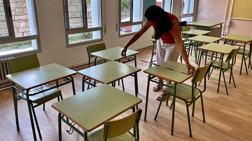 Una profesora mide la distancia entre pupitres en un centro educativo.