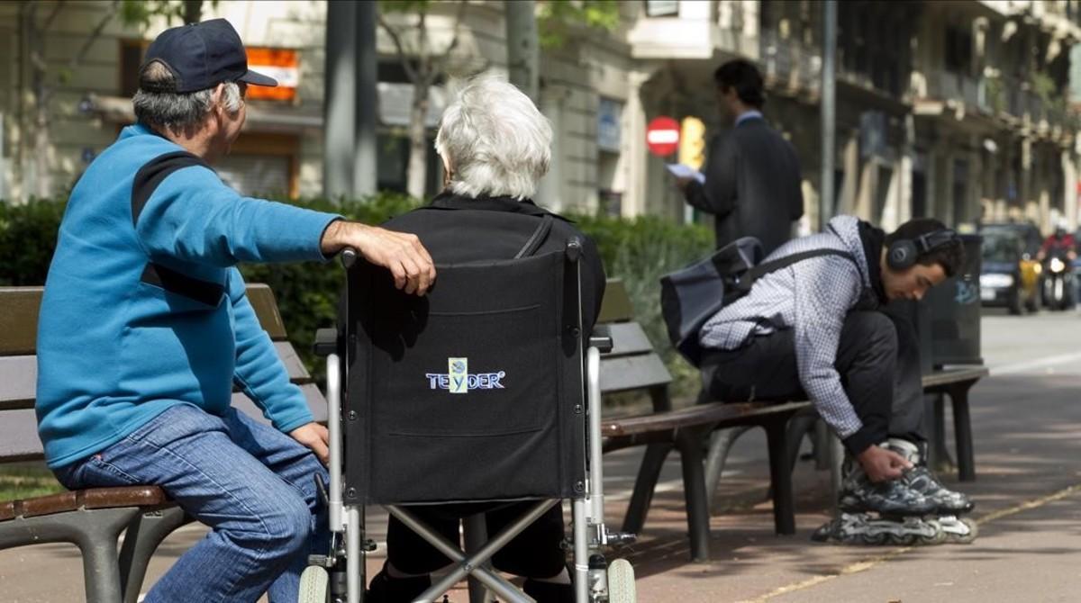 Una anciana con su cuidador en el paseo Sant Joan de Barcelona, en el 2011.