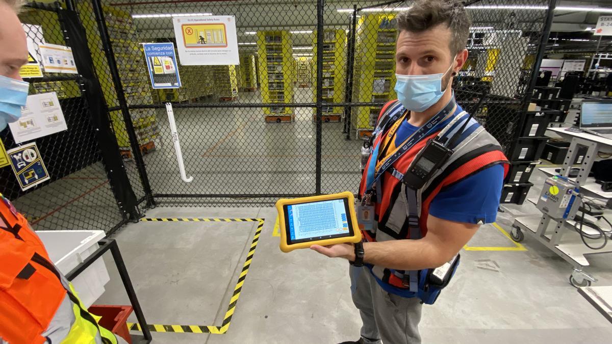 Un trabajador de Amazon muestra la tableta de control de la instalación robotizada de El Prat.