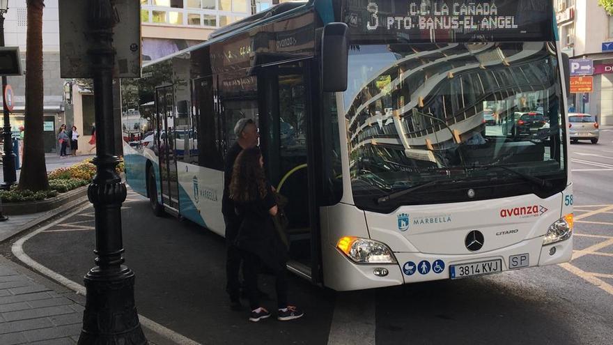 Dos viajeros se suben a un autobús urbano en una de las paradas del centro de Marbella.