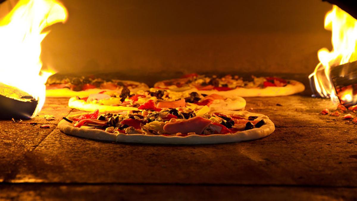 Una pizza preparándose en un horno de leña.