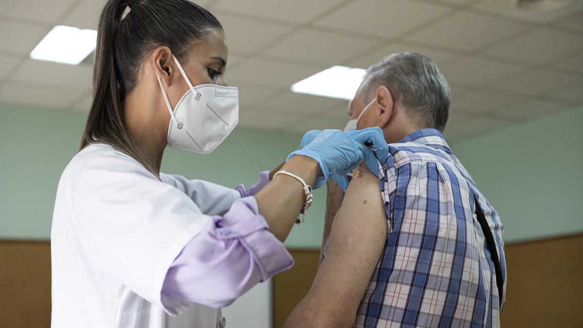 Archivo - Una enfermera vacuna a un hombre contra la gripe y el Covid.