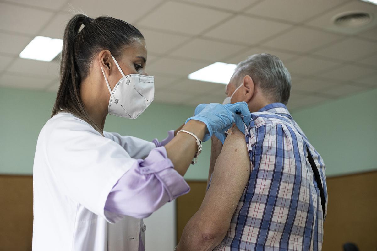 Archivo - Una enfermera vacuna a un hombre contra la gripe y el Covid.