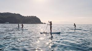 Un grupo practica paddle surf en una playa de Lloret de Mar