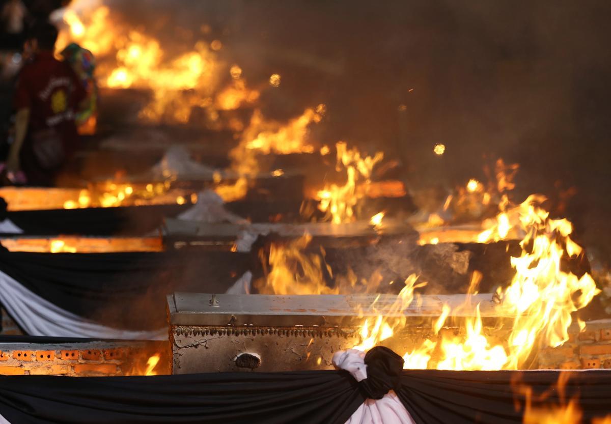 La gente observa cómo las piras funerarias incineran a 19 víctimas del tiroteo en la guardería de Uthai Suwan en el templo Wat Rat Samakee en Uthai Sawan. Un exoficial de policía disparó y mató a 37 personas, al menos 24 de ellos niños, después de irrumpir en una guardería infantil en el noreste de Tailandia.