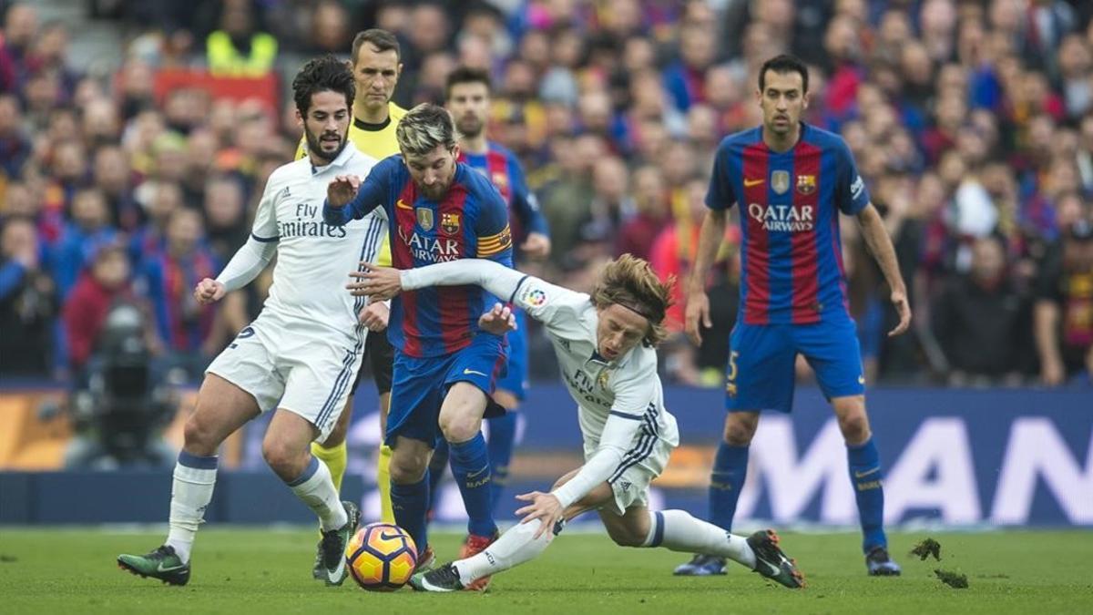 Messi intenta superar a Isco y Modric ante la mirada de Busquets.