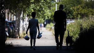 Un niño regresa a casa tras recoger dos bolsas de comida. 