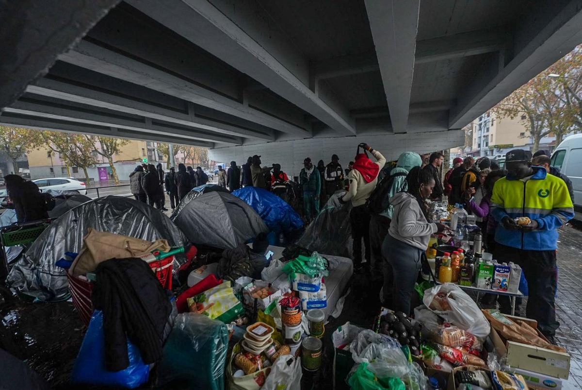 Algunos de los desalojados del B9, instalados con tiendas de campaña bajo una salida de la C-31 en Badalona para protegerse de la lluvia