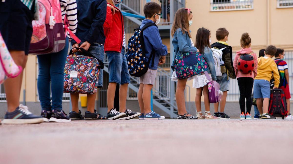 Un grupo de niños de un colegio espera para entrar el clase el primer día de colegio.