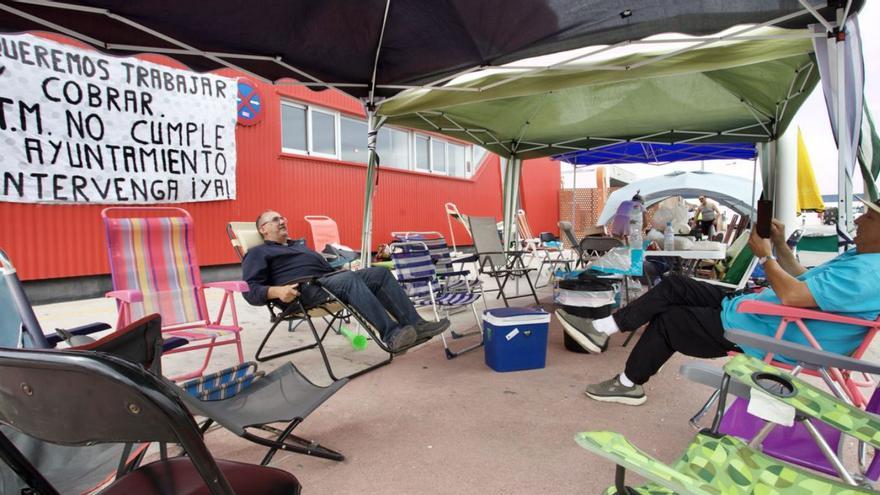 Pérgolas y sillas de playa en la ‘acampada’ de los conductores  en el exterior de las cocheras. | JUAN CARLOS CAVAL