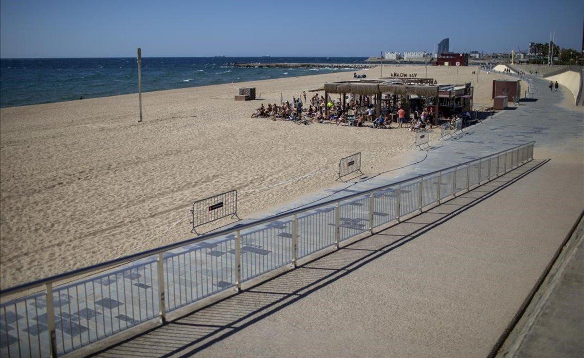 Clientes en un chiringuito de la playa de Barcelona. El resto de la playa permanece vacía.