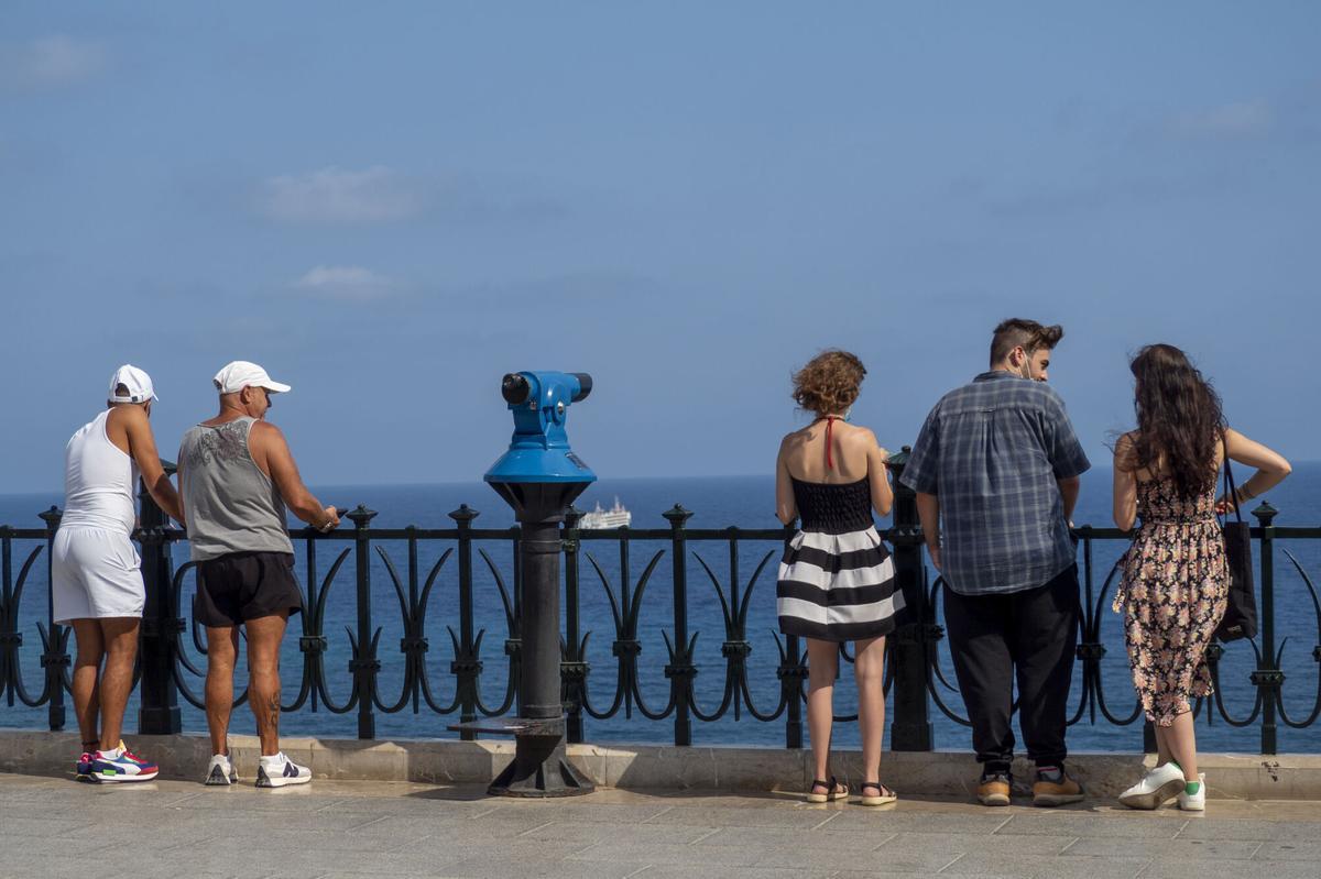 Varios turistas en una barandilla mirando el mar en una localidad de la Costa Daurada, en Tarragona.